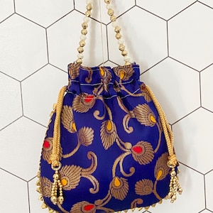 May include: A small, blue drawstring bag with a gold beaded handle and gold trim. The bag is decorated with a floral pattern in gold and red.