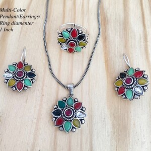 May include: A multi-color jewelry set featuring a pendant, earrings, and ring. The set includes a silver-toned necklace with a pendant, matching earrings, and a ring. Each piece has a floral design with red, green, yellow, and white gemstones. The ring diameter is 1 inch.