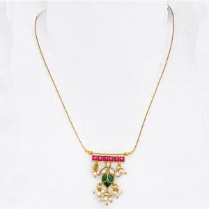 May include: A gold chain necklace with a pendant featuring a green and pink stone design with white pearl accents.