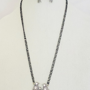 May include: A silver necklace with a bird pendant and black beads. The pendant features two birds perched on a branch with leaves and white stones.