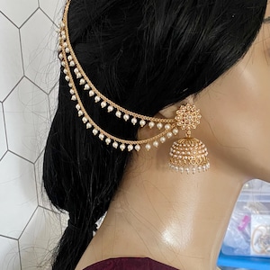 May include: Gold-toned ear cuff and earring set with dangling faux pearls. The earring features a floral design and a bell shape, with multiple strands of pearls. The headpiece has a chain that goes over the head.