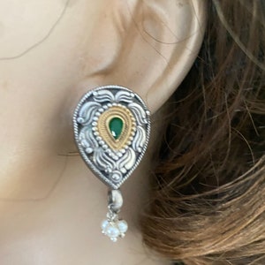 May include: Silver and gold tone teardrop earrings with a green stone and pearl accents.