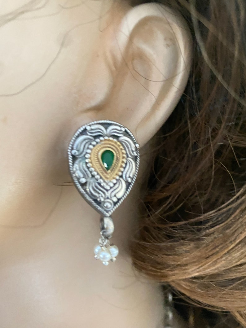 May include: Silver and gold tone teardrop earrings with a green stone and pearl accents.