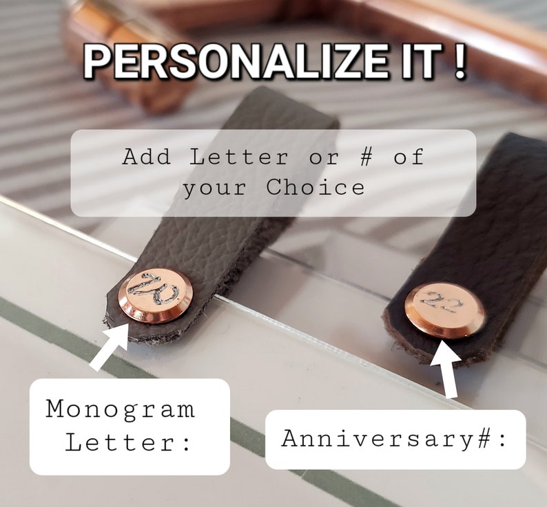 May include: Two gray leather tabs with a copper colored metal disc. The left tab has the letter "W" engraved on the disc. The right tab has the number "22" engraved on the disc. The text "PERSONALIZE IT!" is above the tabs. The text "Add Letter or # of your Choice" is below the tabs. The text "Monogram Letter:" is below the left tab. The text "Anniversary #:" is below the right tab.