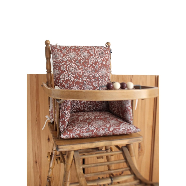 Pode incluir: Uma cadeira alta de madeira com um assento acolchoado estampado floral vermelho e branco e uma bandeja. A cadeira tem um encosto em forma de escada e uma bandeja remov&iacute;vel.