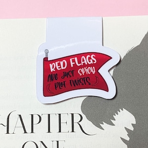 Peut inclure: Signet rouge avec un fond blanc et une bannière rouge qui dit "Les drapeaux rouges ne sont que des rebondissements épicés de l'intrigue".