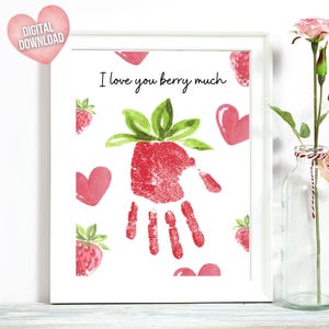 Könnte beinhalten: Ein druckbarer Kunstdruck mit einem roten Handabdruck in Form einer Erdbeere. Der Druck enthält den Text "Ich liebe dich sehr" und ist von roten Herzen und Erdbeeren umgeben.