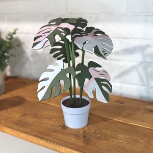 May include: A set of three ceramic mugs with a speckled, matte finish. The mugs are in shades of cream, light gray, and dark gray. Each mug has a simple, minimalist design and a rounded handle.