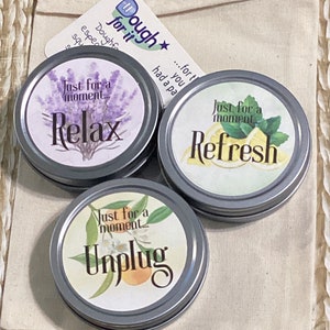 May include: Three silver tins with colorful labels and the text "Just for a moment..."  The labels read "Relax", "Refresh", and "Unplug".