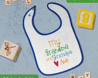 May include: White baby bib with blue trim, featuring the text "my grandma and grandpa Me" in colorful embroidered letters with a red heart.