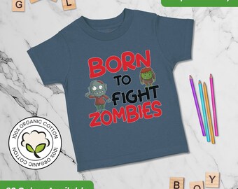 May include: A blue short-sleeved t-shirt with the text "Born to Fight Zombies" in red. The text is surrounded by cartoon images of zombies. The shirt is made of 100% organic cotton.
