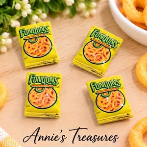 May include: Four miniature yellow Funyuns snack bags featuring green text and a circular window displaying onion flavored rings. The bags are arranged on a light wooden surface alongside loose onion rings and a white bowl of snacks.