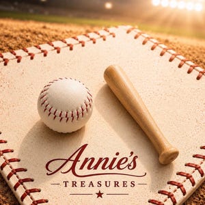 May include: A baseball and a wooden bat rest on a baseball base with red stitching. The image features the text "Annie's Treasures" in a decorative font. The background is a baseball field.