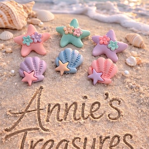 May include: A beach scene with colorful starfish and seashell decorations. The starfish are pastel pink, green, and purple, adorned with flower accents. The text "Annie's Treasures" is written in the sand.
