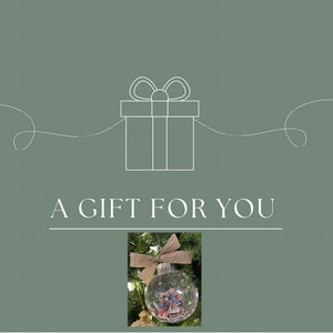 Puede incluir: Una tarjeta de regalo verde con un contorno blanco de una caja de regalo con un lazo en la parte superior. El texto "A GIFT FOR YOU" está escrito debajo de la caja de regalo. Un adorno navideño con una cinta dorada se encuentra en la esquina inferior derecha de la tarjeta.
