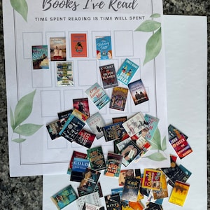 Op de afbeelding: Een wit bord met de tekst "Books I've Read" en "Time Spent Reading is Time Well Spent" bovenaan. Het bord is verdeeld in een raster met vierkanten. Elk vierkant heeft een miniatuur boekomslag erop geplaatst. De boekomslagen zijn in verschillende kleuren en genres. Er zijn ook miniatuur boekomslagen verspreid rond het bord.