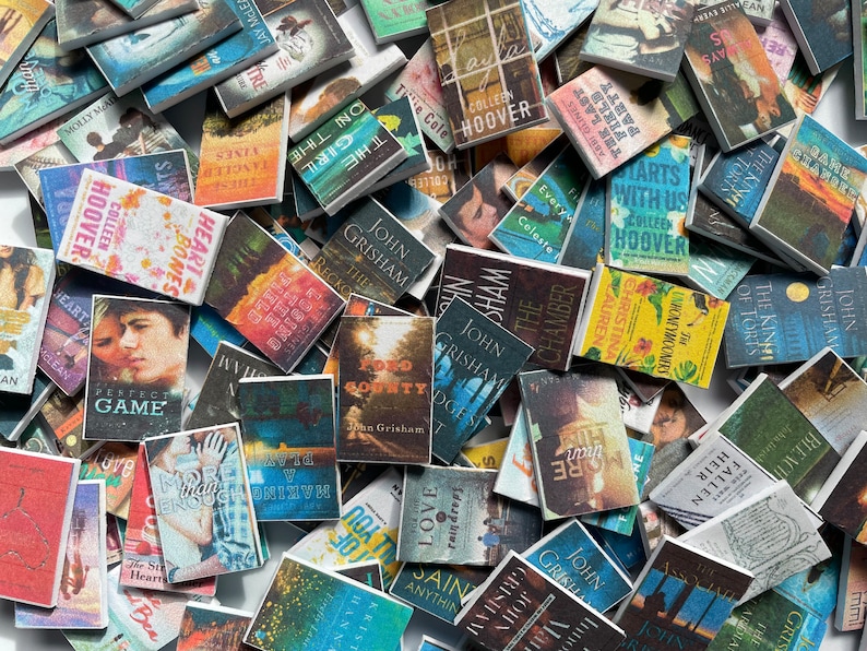Puede incluir: Una colecci&oacute;n de libros de bolsillo en miniatura con varios t&iacute;tulos y autores. Los libros est&aacute;n dispuestos en un patr&oacute;n aleatorio, creando una exhibici&oacute;n colorida y visualmente atractiva.
