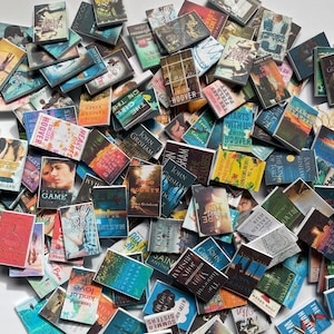 Puede incluir: Una colecci&oacute;n de libros de bolsillo en miniatura con varios t&iacute;tulos y autores. Los libros est&aacute;n dispuestos en una pila, con algunos superpuestos. Los libros son de diferentes colores y tienen diferentes dise&ntilde;os.