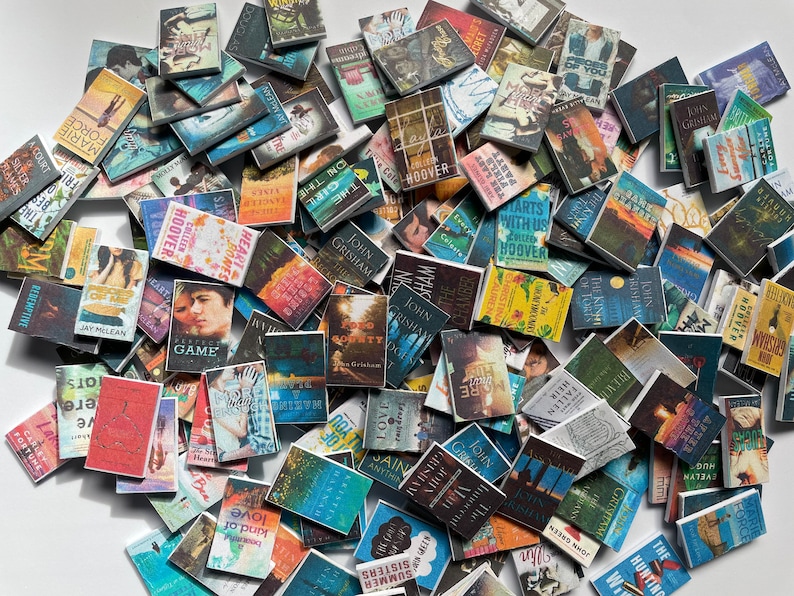 Puede incluir: Una colecci&oacute;n de libros de bolsillo en miniatura con varios t&iacute;tulos y autores. Los libros est&aacute;n dispuestos en una pila, con algunos superpuestos. Los libros son de diferentes colores y tienen diferentes dise&ntilde;os.
