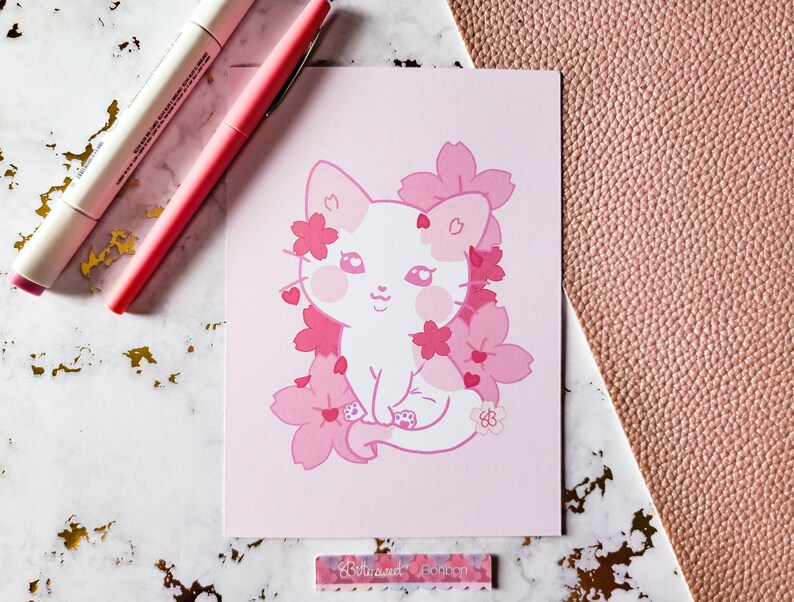 K&ouml;nnte beinhalten: Eine rosa und wei&szlig;e Illustration einer Katze, die in einem Bl&uuml;tenmeer aus rosa Kirschbl&uuml;ten sitzt. Die Katze hat eine rosa Nase und rosa Wangen. Die Illustration ist auf rosa Hintergrund.