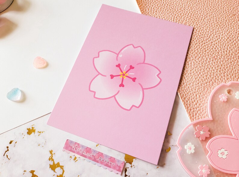 May include: A pink card with a pink cherry blossom illustration. The card has a white border and the text "Betwixtweed Bonbon" is printed on the bottom.