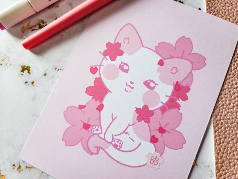 K&ouml;nnte beinhalten: Eine wei&szlig;e Katze mit rosa Wangen und einer rosa Nase ist von rosa Kirschbl&uuml;ten umgeben. Die Katze hat ein rosa Herz am Ohr und ein rosa Herz am Schwanz. Der Hintergrund ist rosa.