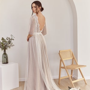 An ivory tulle wedding dress with a lace bodice and a dotted tulle skirt. The dress has a low back and a train.