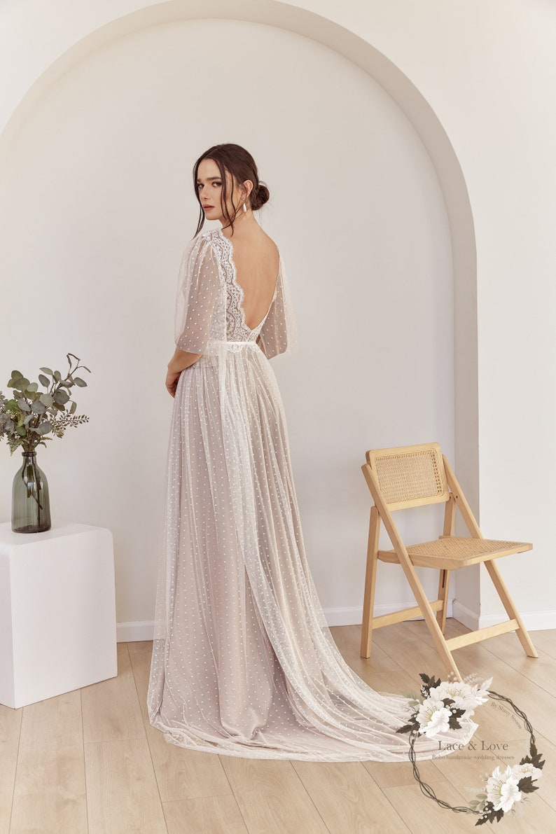 An ivory tulle wedding dress with a lace bodice and a dotted tulle skirt. The dress has a low back and a train.