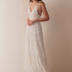 May include: A white sleeveless maxi dress with lace detailing and a V-neckline.
