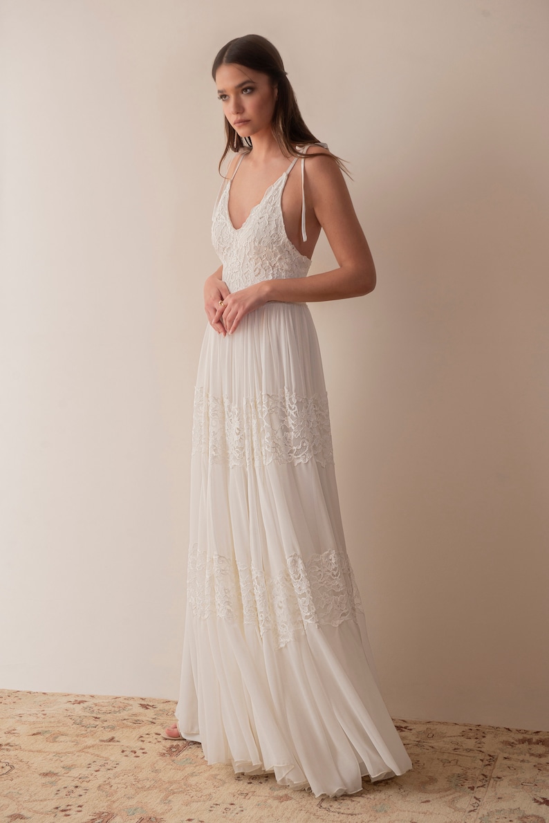 May include: A white sleeveless maxi dress with lace detailing and a V-neckline.