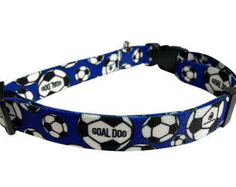 Può includere: Collare per cani blu con un motivo a pallone da calcio bianco e nero. Il collare ha una fibbia nera e il testo "GOAL DOG" è stampato sul collare.