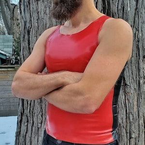 Peut inclure: Un débardeur rouge sans manches avec une bordure noire sur les côtés. Le débardeur est fait d'un matériau brillant et lustré.