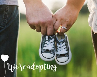 May include: A couple holds a pair of baby shoes in their hands, with the text "We're adopting" written below. The image is a symbol of adoption and new beginnings.