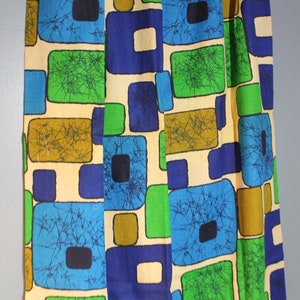 May include: A fabric with a geometric pattern of squares in shades of blue, green, brown, and cream. The squares are outlined in black and have a textured, almost spiderweb-like design.