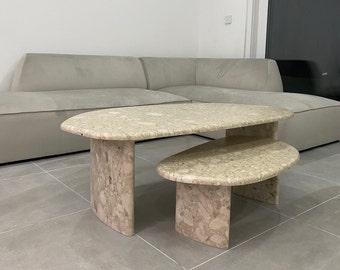 Peut inclure: Un ensemble de tables basses gigognes en pierre beige mouchetée. L'ensemble comprend une grande table ovale et une table plus petite et basse, toutes deux dotées de pieds en forme de dalle incurvée et d'une surface en pierre naturelle polie.