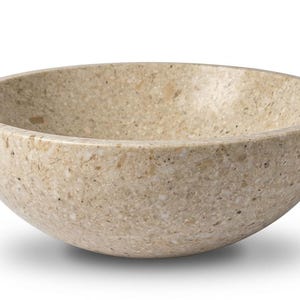 Peut inclure: Un bol rond fabriqué dans un matériau composite de couleur beige moucheté. La surface présente un motif texturé composé de petits éclats de tons crème, brun clair et beige incrustés uniformément dans toute la structure solide du récipient.