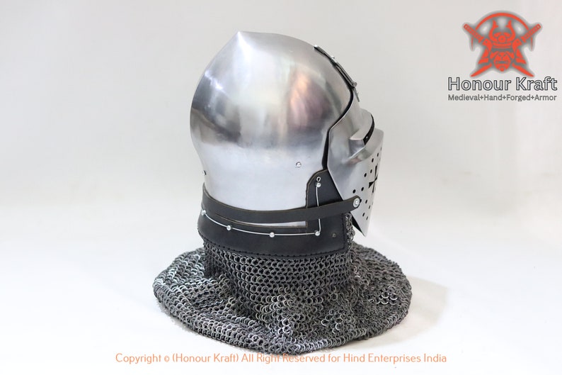May include: A silver helmet with a face mask and a chainmail coif. The helmet has a pointed top and a leather strap around the bottom. The helmet is on a white background.