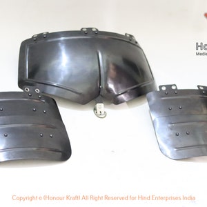 May include: Three pieces of black metal armor, including a chest plate and two smaller plates. The armor is hand-forged and has a smooth, polished finish.