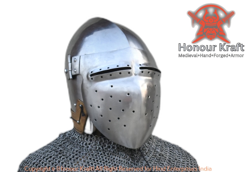 May include: A silver helmet with a visor and a chainmail collar. The helmet has a series of small holes throughout the visor and a hinged visor. The helmet is made by Honour Kraft, a company that specialises in hand-forged medieval armour.