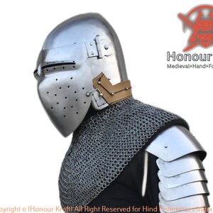 May include: A silver helmet with a visor and a brown leather strap. The helmet is worn by a person wearing chainmail and a silver shoulder piece. The text "Honour Kraft Medieval+Hand+Forged+Armor" is visible in the upper right corner of the image.