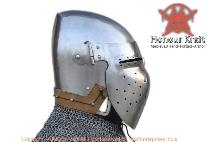 May include: A side view of a medieval helmet with a visor and a leather strap. The helmet is made of metal and has a textured surface. The helmet is a hand-forged piece of armour.