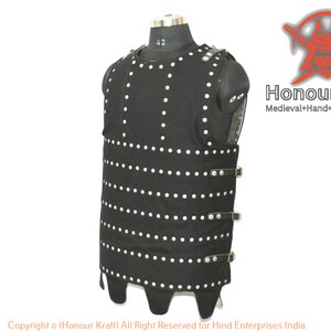 May include: A black leather vest with silver rivets and buckles. The vest has a pointed bottom and is designed to look like medieval armor. The text "Honour Kraft" is visible in the image.