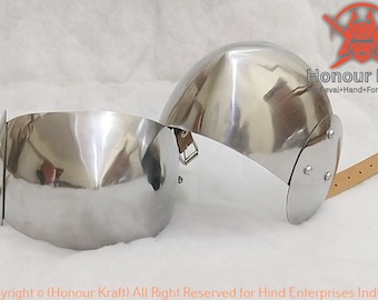 May include: Two silver metal elbow guards with leather straps. The guards are curved and have a smooth, polished finish. The straps are brown leather and have buckles.