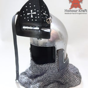 May include: A medieval helmet with a chainmail coif and a visor. The helmet is made of steel and has a cross design on the visor. The helmet is on a white background.