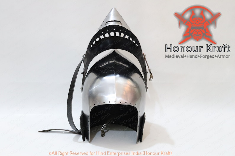 K&ouml;nnte beinhalten: Ein silberner Helm mit einer spitzen Spitze und einem schwarzen Lederriemen. Der Helm hat ein Visier, das angehoben oder abgesenkt werden kann. Der Helm ist aus Metall und hat eine strukturierte Oberfl&auml;che. Der Helm ist ein Helm im mittelalterlichen Stil.