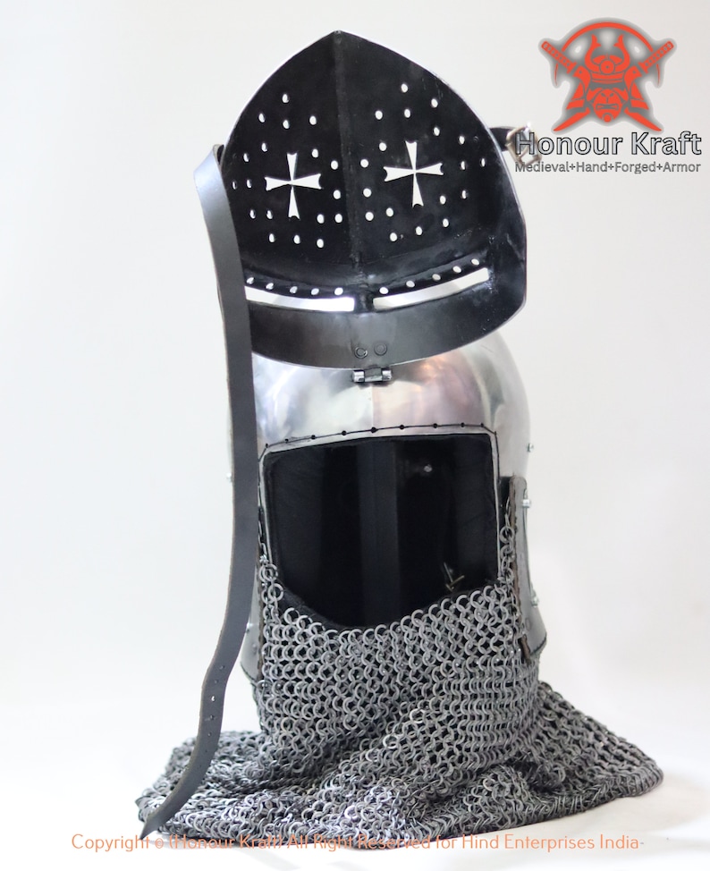 May include: A silver helmet with a black visor and a chainmail coif. The helmet has a cross design on the visor and the text "Honour Kraft" is visible on the right side of the image.