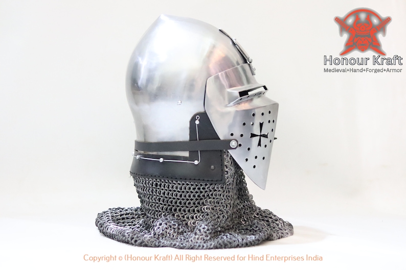 May include: A silver helmet with a faceplate and a chainmail coif. The helmet has a cross on the faceplate and is made of metal. The helmet is on a white background.