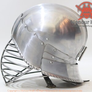 Op de afbeelding: Een zilveren helm met een vizier en een nekbeschermer. De helm is gemaakt van metaal en heeft een gladde, gepolijste afwerking. De helm is een type middeleeuwse armor.