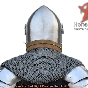 May include: A medieval helmet with a pointed top and a brown leather strap. The helmet is made of metal and has a chainmail collar. The helmet is worn by a person, but the person's face is not visible. The image is taken from the back of the helmet.