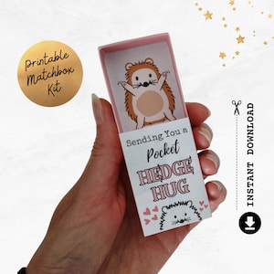 May include: A printable matchbox kit with a hedgehog design. The matchbox is pink and has the text "Sending You a Pocket Hedge Hug" on the front.